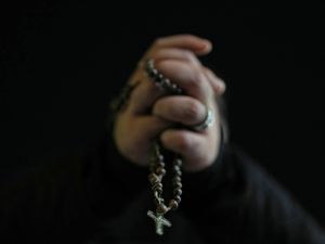 One of the faithful holds a rosary