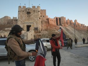 Two fighters burning the Syrian flag outside a castle