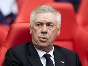 Carlo Ancelotti sits on the touchline before a game