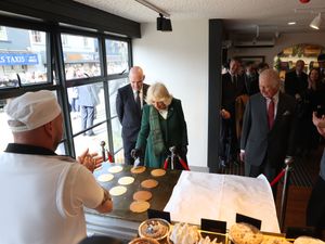 Charles and Camilla help during a demonstration of the production of Ulster Scots Crumpets at Hunters Bakery in Limavady