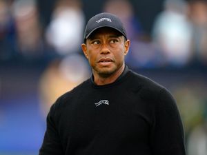 Tiger Woods wearing a black jumper and black cap