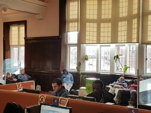 Taking a nap – The group of men sleep on sofas while library users in the foreground use the communal computers