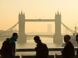 Commuters are seen with Tower Bridge, in central London as they cross London Bridge during morning rush hour.