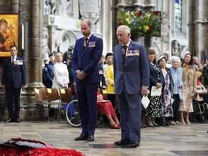 Prince of Wales and King Charles pause in front of poppies, inside Westminster Abbey
