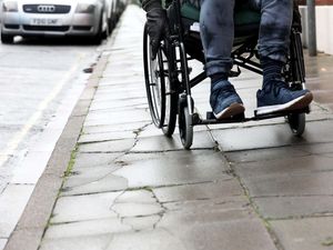 A man in a wheelchair pictured using it along an uneven path in London