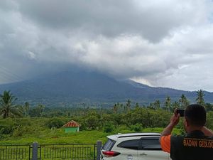 Rising column of smoke from a volcano as someone takes a picture