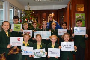 Alexandra with a few of the children who helped her over the line, with banners for all of the charities they are benefitting