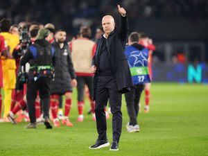 Arne Slot acknowledges the fans in the stands as Liverpool players celebrate in the background