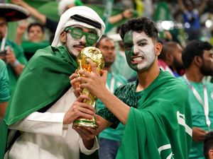 Saudi Arabian fans pose with a replica World Cup trophy at a match against Mexico at the 2022 finals