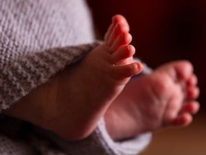 The feet of a baby wrapped in a blanket.