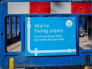 A sign next to a hole in the ground from Thames Water supply company stating "We're fixing pipes"