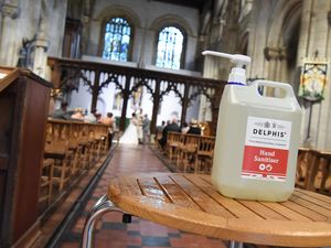 A bride and groom in church with hand sanitiser in the foreground