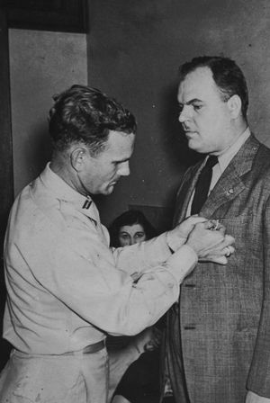 Wayne Byer is presented with a medal or a badge.