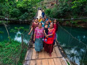 Women from rural Guatemala cross a bridge built to get them across the river