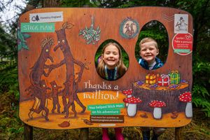 Two young children with their faces through a Stick Man trail panel