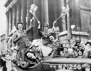 Members of the Women's Royal Army Corps drive their service vehicle through Trafalgar Square waving flags in celebration of victory