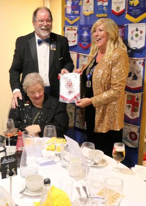 Lion President Debra Coburn presenting 2nd Vice District Governor Ken Topping with a Rugeley and District Lions Club Banner. 