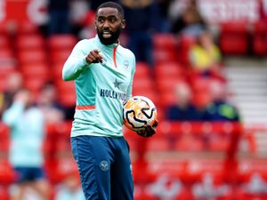 Justin Cochrane, holding a ball, points during a Brentford warm-up