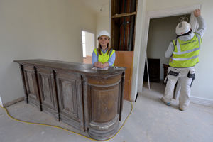 Chloe Taylor poses on the upstairs bar as work goes on around her