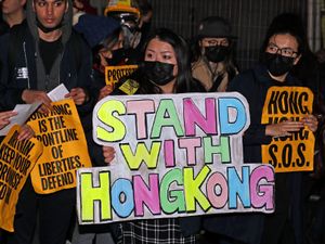 A woman holding a sign reading 'Stand with Hong Kong' during a Hong Kong democracy protest in Trafalgar Square