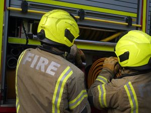 Two firefighters unfurling a hose from a fire engine