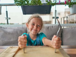 Child with a knife and fork in the restaurant