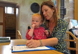 Rebecca Richards signs the Shropshire Star mobile phone petition at Shrewsbury Library with daughter Annabella