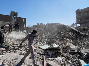 A group of men inspect the ruins of a police station in Iran