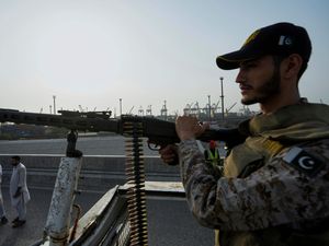 A paramilitary soldier stands alert on a vehicle at a road near Karachi port