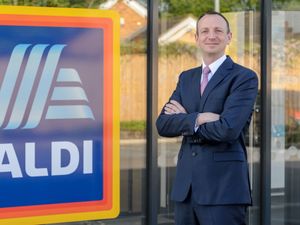 Aldi boss Giles Hurley standing next to the logo