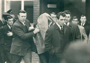 Raymond Morris hides under a coat as he is led into court