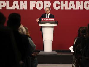 Prime Minister Sir Keir Starmer in front of a red background featuring the slogan Plan for Change