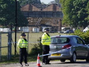Police in front of damaged buildings following a fire at Bicester Motion
