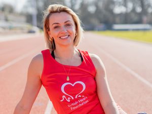 Lisa McGrillis smiling while wearing a red British Heart Foundation running vest at a track