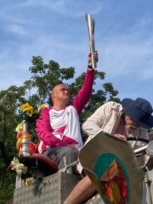 Community First Responder Mark Jones from Broseley holds the baton aloft in Ironbridge