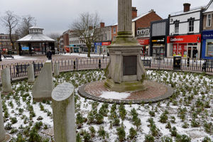 Snow scattered between the plants around the war memorial in Cannock town centre