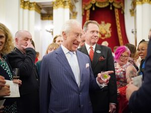 Charles, centre, laughing while holding a drink during a reception in Buckingham Palace