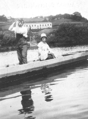 The old ferry at Ironbridge, aka Benthall Edge ferry. In the background on the Ironbridge side of the River Severn is a building known as 'The Grand Hall' and built by the Coalbrookdale Company around 1924, says Mrs D. Wozencroft, who loaned this picture. It was built as a social club and used for dances and other social occasions. Now demolished. Merrythought had started in offices there, about 1928, she says. On the ferry is ferryman Mr Beddoes, and Mrs Wozencroft's unnamed cousin from Leeds, who was on holiday.