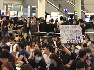 A protestor holds a placard in the crowds at Hong Kong airport. Picture: Krissi Carter