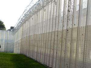 A guard patrolling a fence inside a prison
