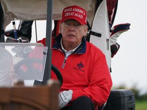 Donald Trump in a golf cart, wearing a 'Make American great again' cap