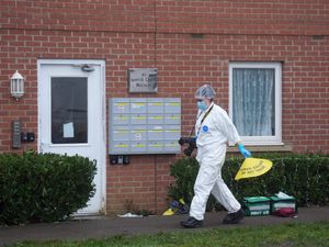 Forensic officer in white protective suit outside a property