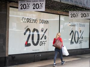 A shopper passes closing-down sale signs in a shop