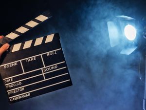 A person holding a clapperboard with studio lights in the background