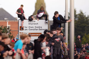 Fans climb on street signs to gain a better view during a victory parade