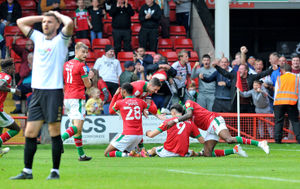 Players mob Conor Wilkinson after he scores the winner.
