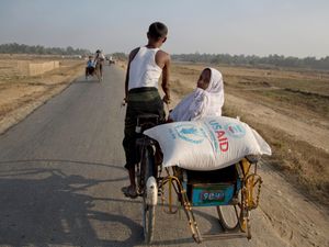 A woman travels on a bicycle cart with a bag of rice