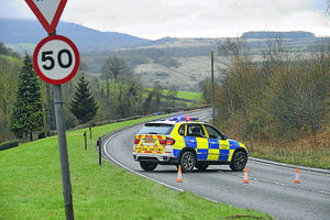 A police car blocks the road after the car crashed into an embankment today