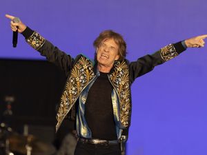 Sir Mick Jagger with his hands in the air on stage
