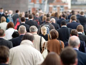 A large crowd of commuters seen from behind during rush hour in the City of London